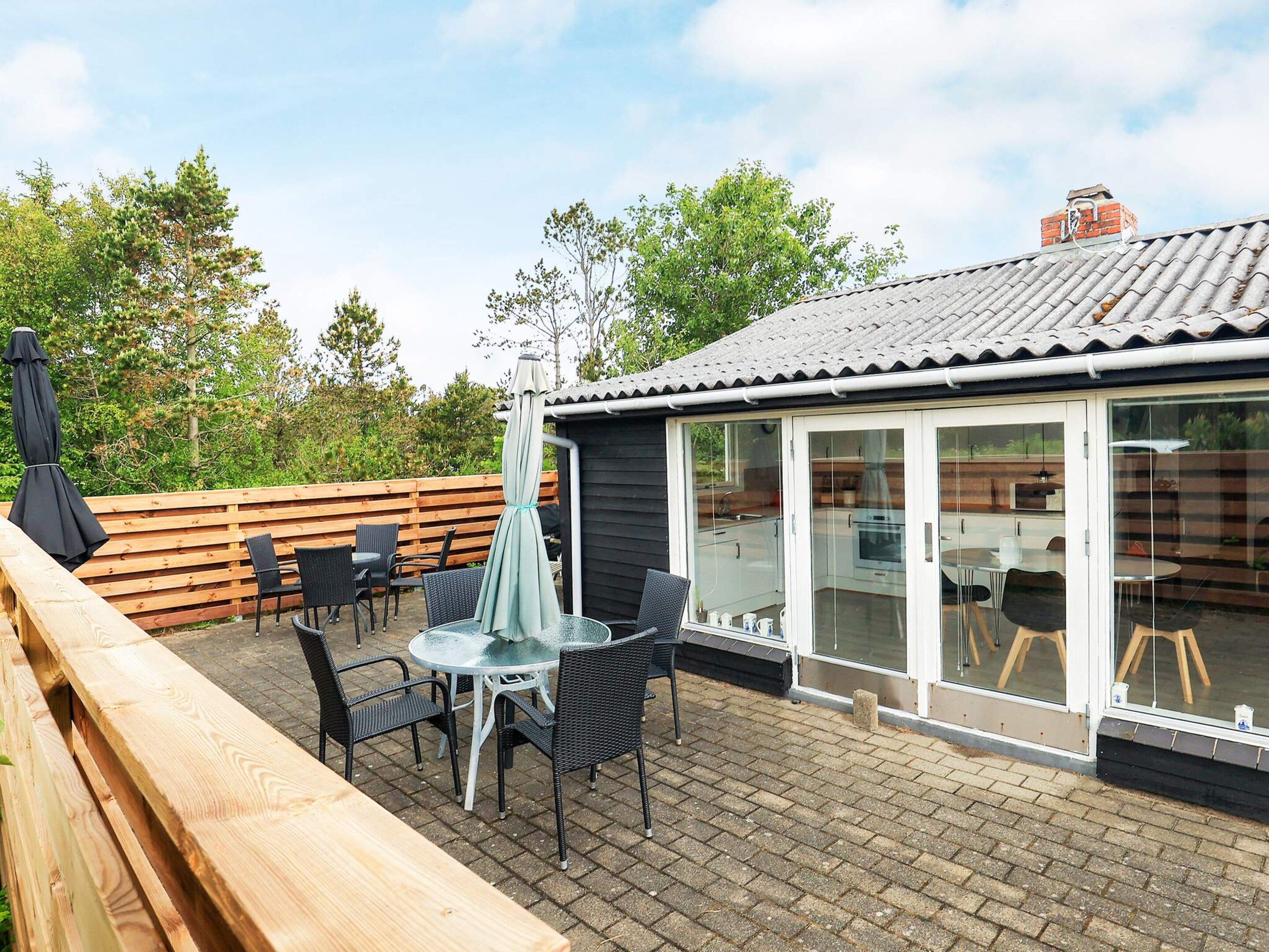 A patio with outdoor furniture, a glass-enclosed dining area, and a wooden deck.