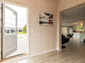 A modern interior with a wooden wall, a painting of a lighthouse, and a view of a building outside. - Spacious Holiday Home in Strøby near Beach (Aalbaek)
