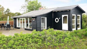 A small, single-story building with a black exterior and white trim, featuring a covered patio area with outdoor seating. - Spacious Holiday Home in Strøby near Beach (Aalbaek)