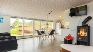 A modern kitchen with a built-in stove, a dining area with a table and chairs, and a TV mounted on the wall. - Spacious Holiday Home in Strøby near Beach (Aalbaek)
