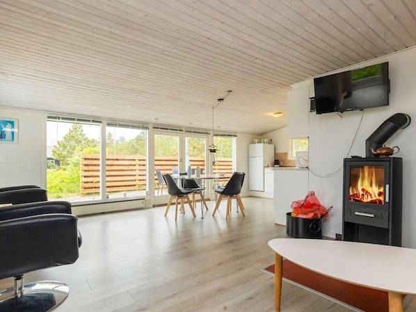 A modern kitchen with a built-in stove, a dining area with a table and chairs, and a TV mounted on the wall. - Spacious Holiday Home in Strøby near Beach (Aalbaek)