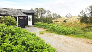 A small black building with a white door, surrounded by green vegetation and a gravel path. - Spacious Holiday Home in Strøby near Beach (Aalbaek)