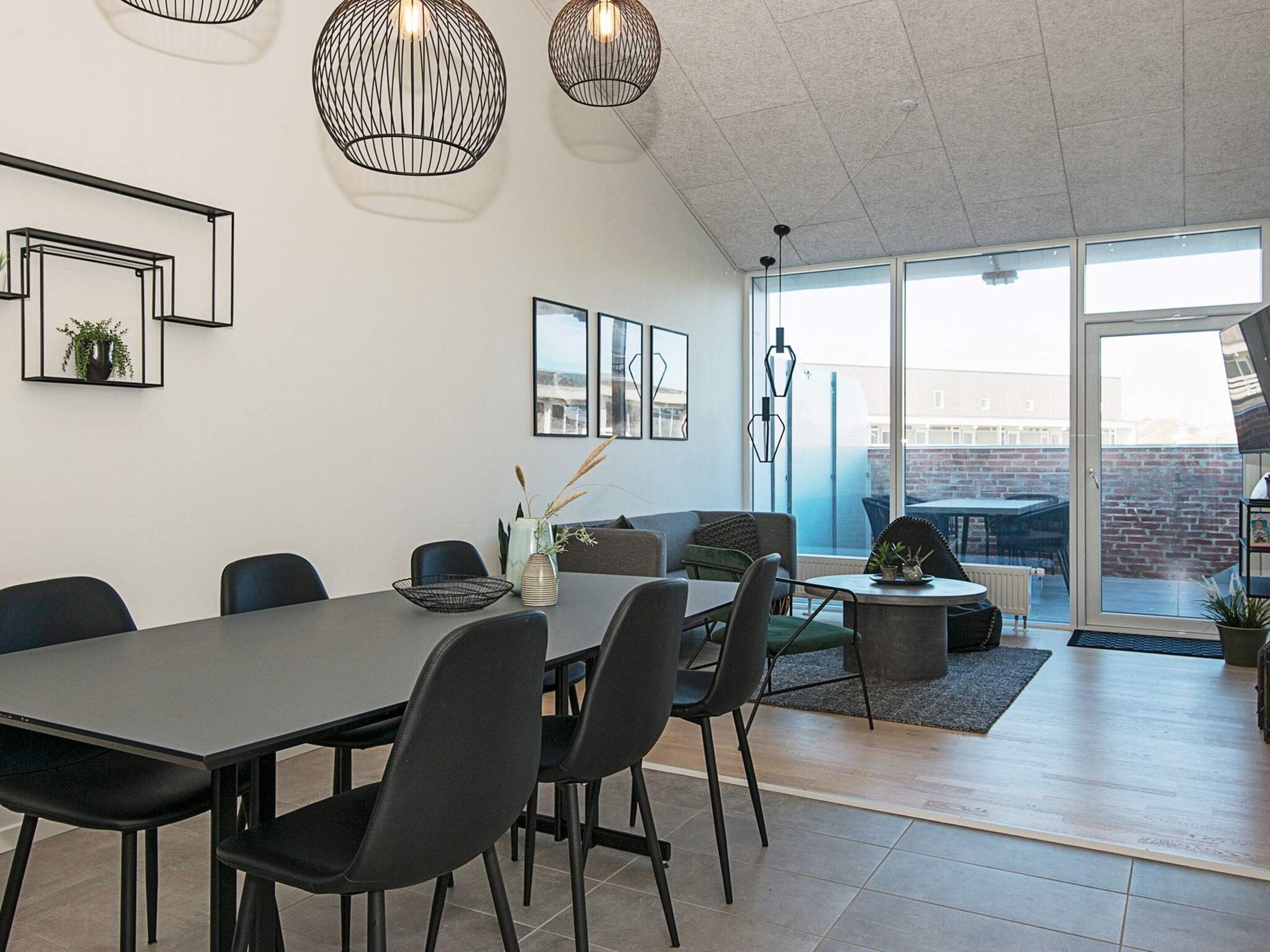 Un comedor moderno con una mesa grande, sillas e iluminación colgante.