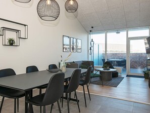 A modern dining area with a large table, chairs, and pendant lighting. - Cozy Holiday Home in Syddanmark near Beach (Ringkobing)