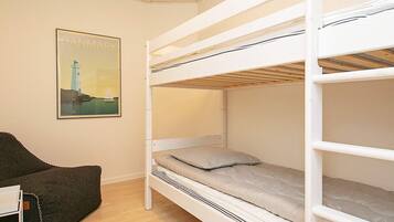 Habitación con literas, un cartel en la pared, una silla y suelo de madera.