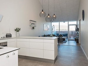 Une cuisine moderne dotĂ©e dâun Ăźlot central, de luminaires suspendus et donnant sur un espace patio.
