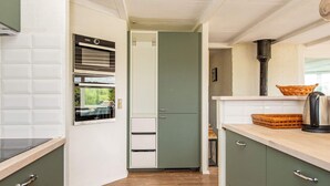 A compact kitchen with a built-in oven, a microwave, and a kettle on the countertop. - 4 Star Holiday Home in Ringkobing (Ringkobing)