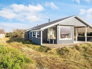 Une maison de plage moderne dotée d’une grande terrasse et d’un espace extérieur couvert.