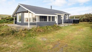 Une maison moderne avec un toit en pente, de grandes fenêtres et une véranda couverte.