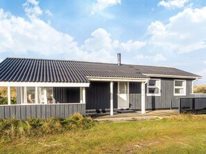 A modern house with a sloped roof, a covered porch, and a fenced yard.