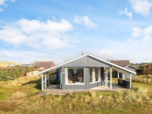 A modern house with a large glass window, a wooden deck, and a number 16 sign.