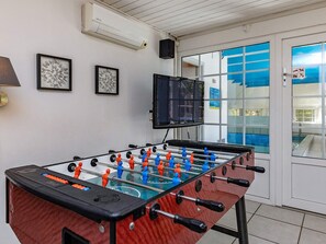 A foosball table in a room with a television, framed artwork, and a door with a window. - 4 Star Holiday Home in Vaeggerlose (Vaeggerlose)