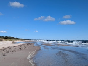 A beach with a clear sky, waves, and a person walking. - 4 Star Holiday Home in Vaeggerlose (Vaeggerlose)