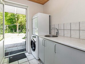 A compact kitchen with a built-in washer, a sink, and a view of the outdoors. - 4 Star Holiday Home in Vaeggerlose (Vaeggerlose)