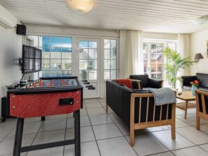 A room with a foosball table, a sofa, a coffee table, and a potted plant. - 4 Star Holiday Home in Vaeggerlose (Vaeggerlose)