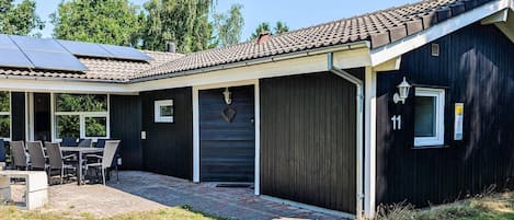 A modern house with a covered patio, solar panels, and a garage.
