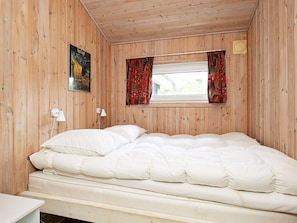 A room with a bed, a window with curtains, a lamp, and a poster on the wall. - 4 Star Holiday Home in Vaeggerlose (Vaeggerlose)