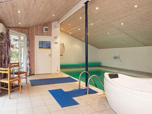 An indoor swimming pool with a hot tub, wooden ceiling, and a door leading outside. - 4 Star Holiday Home in Vaeggerlose (Vaeggerlose)