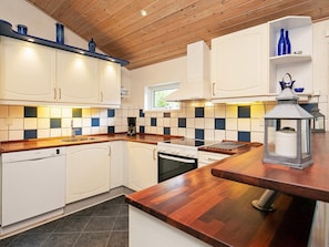 A modern kitchen with white cabinets, a wooden countertop, and a tiled backsplash. - 4 Star Holiday Home in Vaeggerlose (Vaeggerlose)