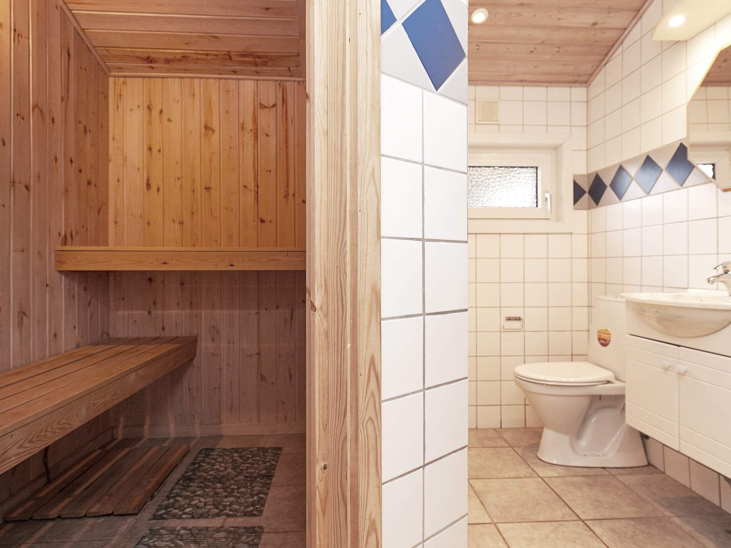 A bathroom with a wooden bench, a toilet, and a sink.