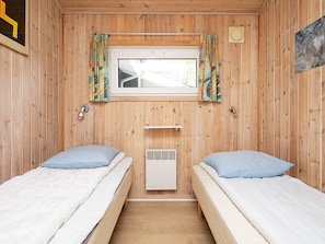 A room with two beds, a window, and a wall-mounted heater. - 4 Star Holiday Home in Vaeggerlose (Vaeggerlose)