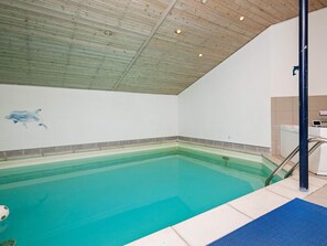 An indoor swimming pool with a wooden ceiling and a dolphin mural on the wall.