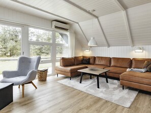 Un salon moderne avec un canapé d’angle, un fauteuil gris et une table basse.