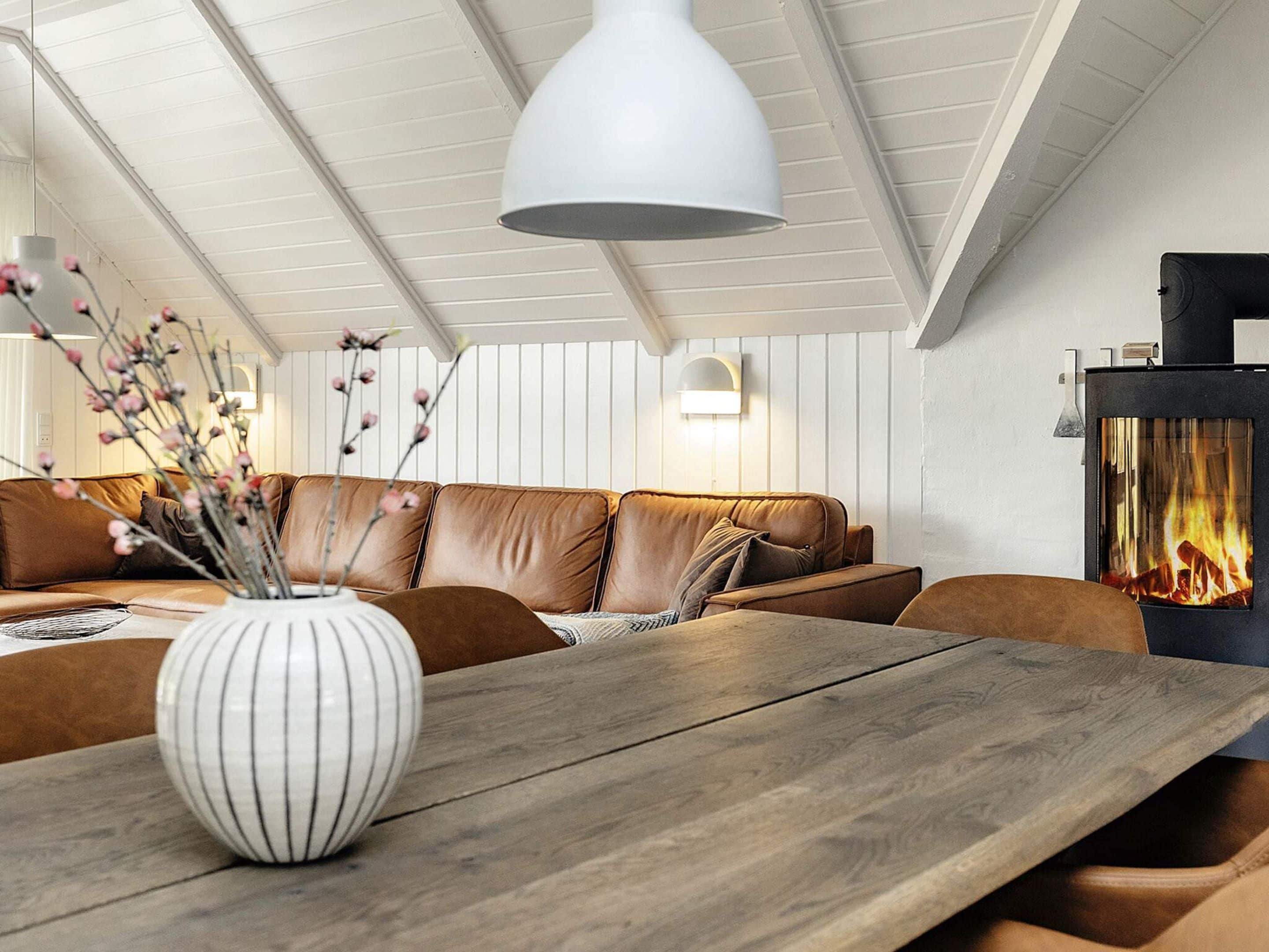 Una sala de estar moderna con una mesa de madera, un sofá de cuero y una chimenea.
