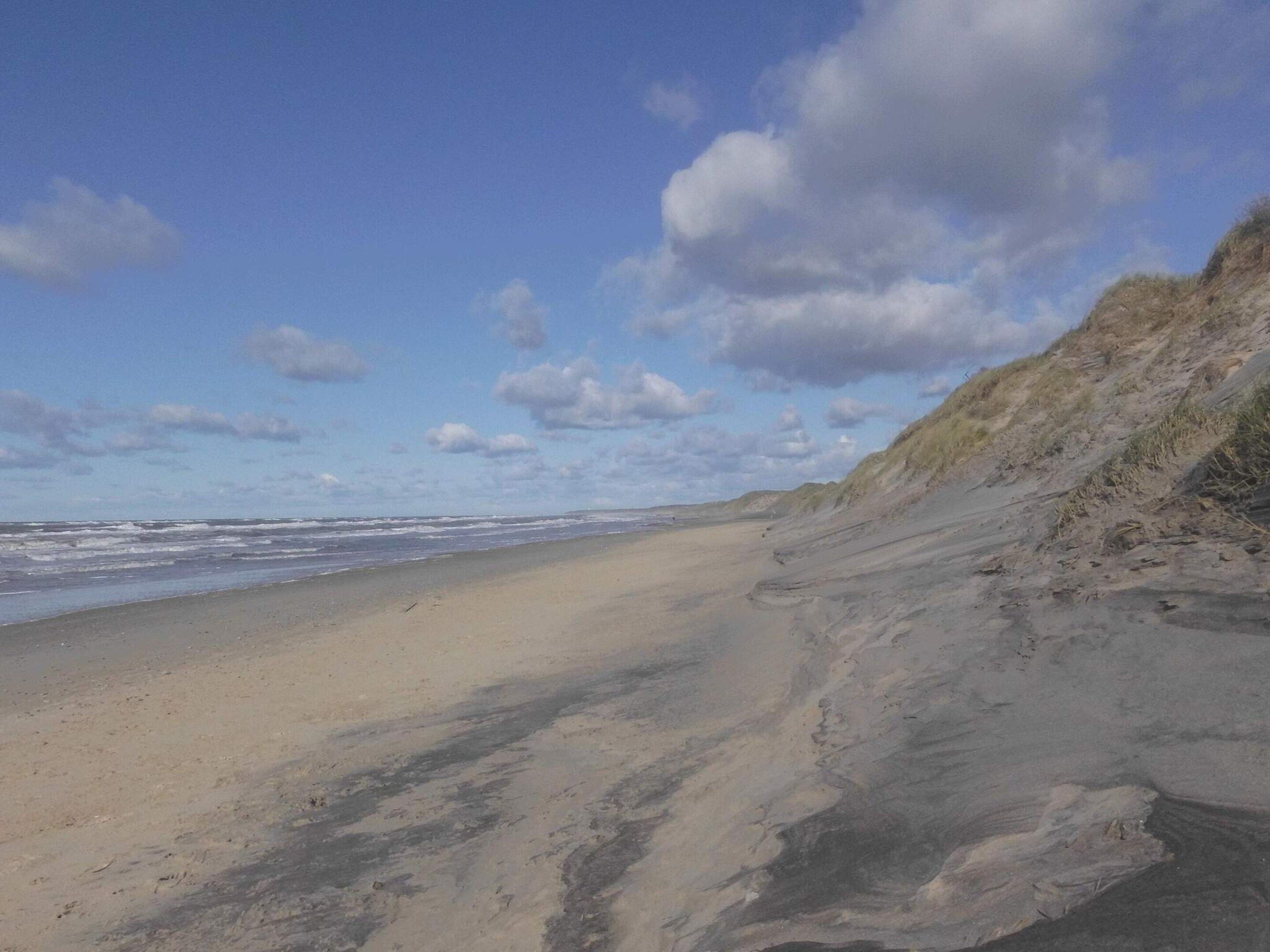 A beach with a sandy shore and a grassy dune.