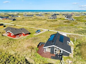An aerial view of a coastal residential area with houses, a clear sky, and the ocean in the background. - 4 Star Holiday Home in Hjorring (Hjørring)