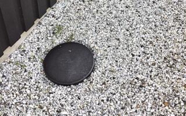 A round, dark-colored object on a gravel surface.