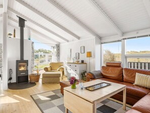 A cozy living room with a fireplace, a sofa, a coffee table, and a view of the outdoors. - 4 Star Holiday Home in Hjorring (Hjørring)