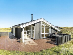 A modern house with a wooden deck, a glass door entrance, and a chimney. - 4 Star Holiday Home in Hjorring (Hjørring)