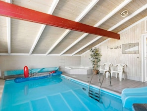 An indoor swimming pool with a blue inflatable raft, a hot tub, and white plastic chairs. - 4 Star Holiday Home in Hjorring (Hjørring)