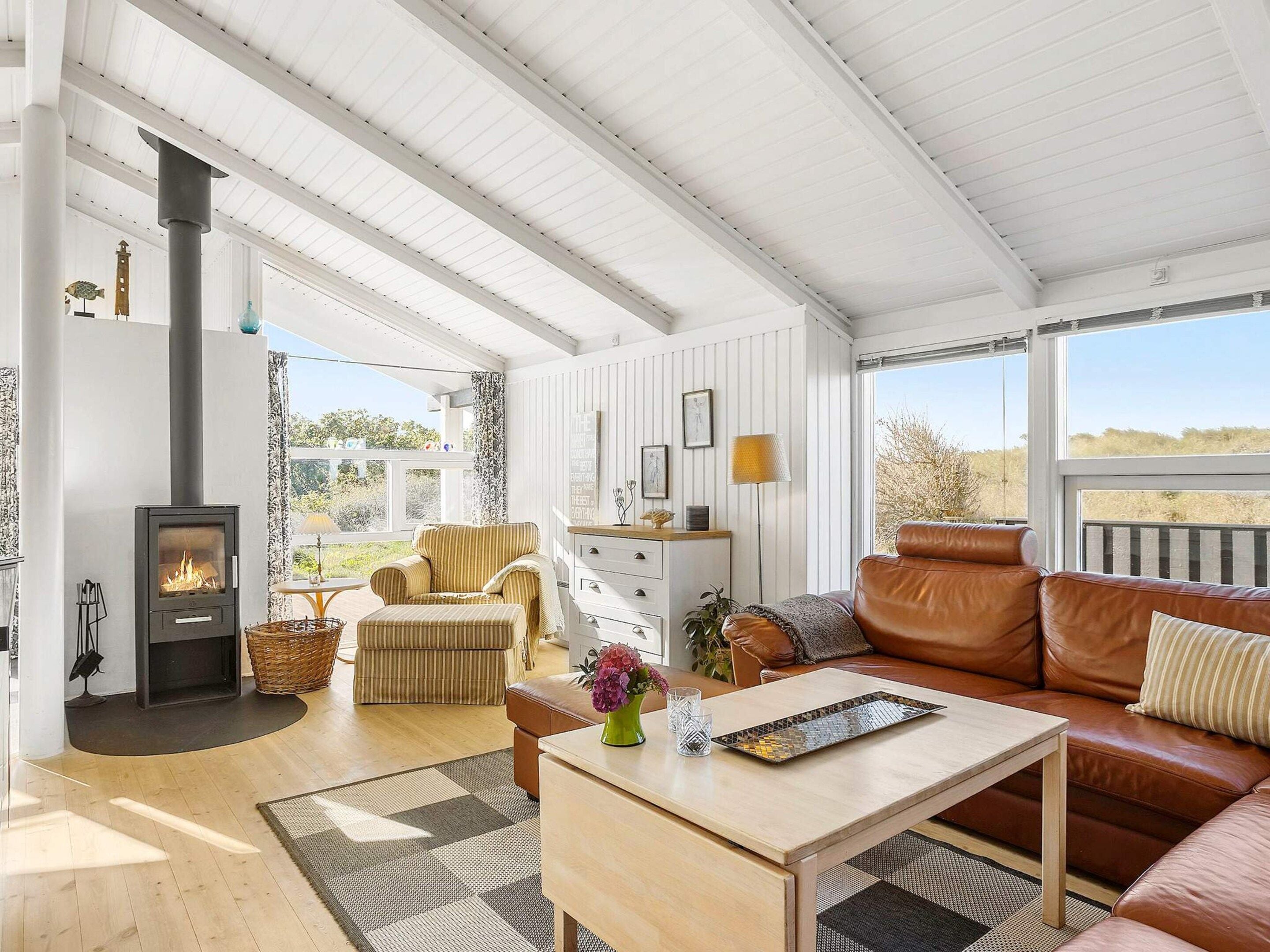 A cozy living room with a fireplace, a sofa, a coffee table, and a view of the outdoors.