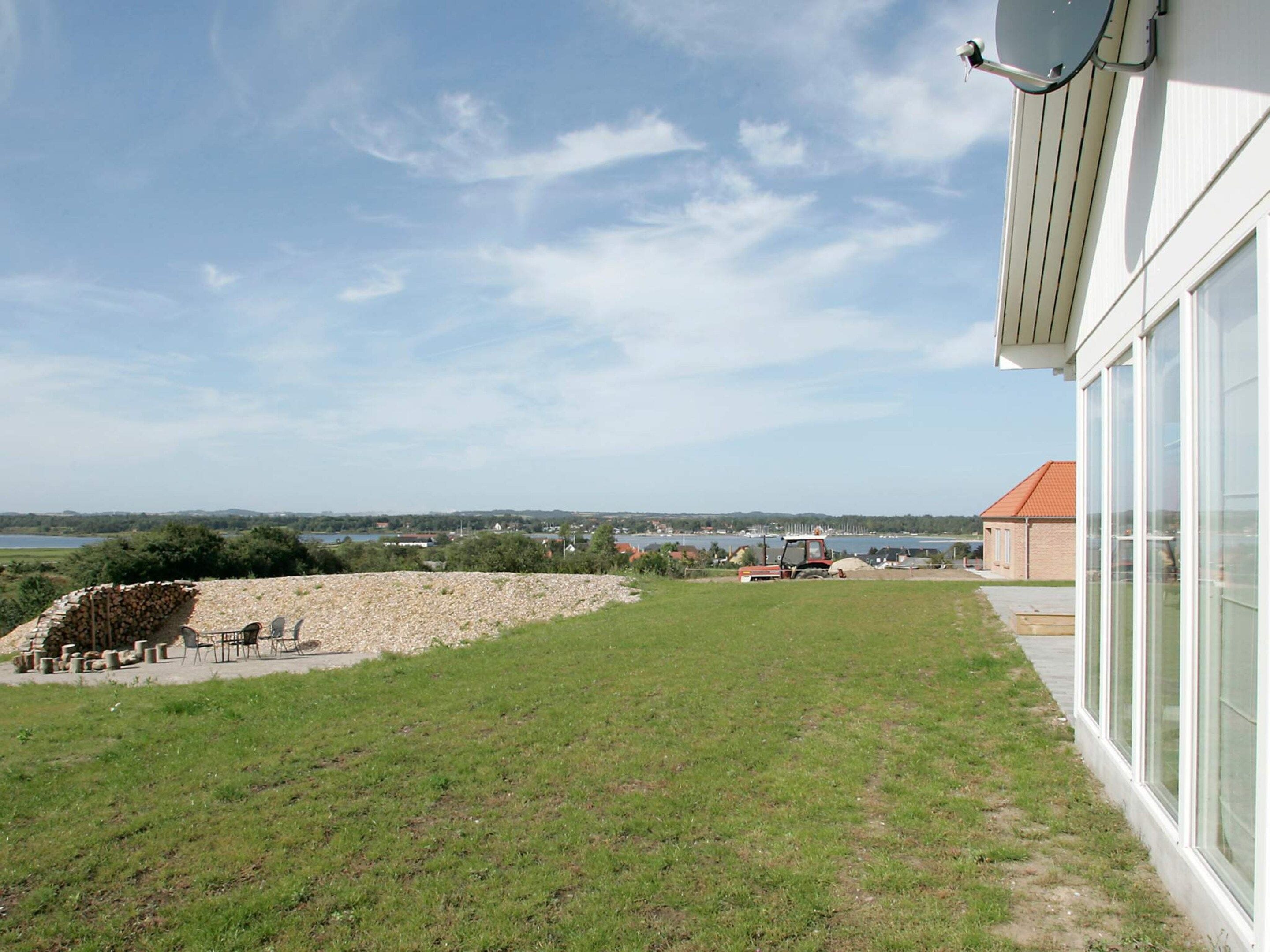 Propiedad residencial con jardín césped, muro de piedra y vista a un paisaje distante.