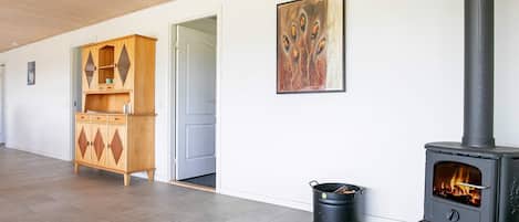 A room with a wood-burning stove, a cabinet, and a painting on the wall.