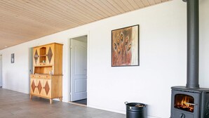 A room with a wood-burning stove, a cabinet, and a painting on the wall. - 4 Star Holiday Home in Skals (Skals)