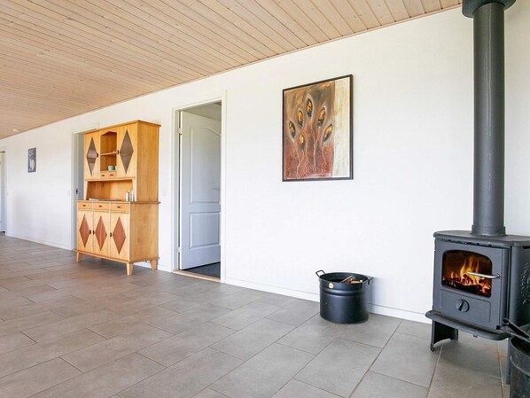 A room with a wood-burning stove, a cabinet, and a painting on the wall. - 4 Star Holiday Home in Skals (Skals)