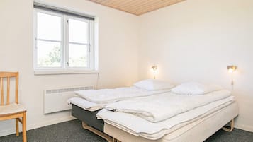 Un dormitorio con cama, una silla, un ventanal y luces en la pared.