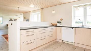 Una cocina moderna con armarios de madera clara, encimera negra y lavavajillas.