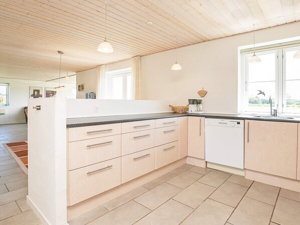 A modern kitchen with light wood cabinets, a black countertop, and a dishwasher. - 4 Star Holiday Home in Skals (Skals)