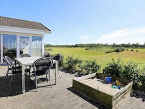 A patio with a table and chairs, a wooden play area, and a view of a green field. - 4 Star Holiday Home in Skals (Skals)