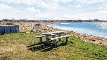 Mesa para piquenique à beira de um lago, com céu claro.