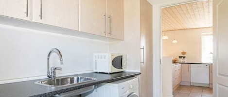 A compact kitchen with a washing machine, a microwave, and a sink.