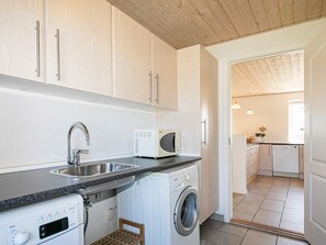 A compact kitchen with a washing machine, a microwave, and a sink. - 4 Star Holiday Home in Skals (Skals)