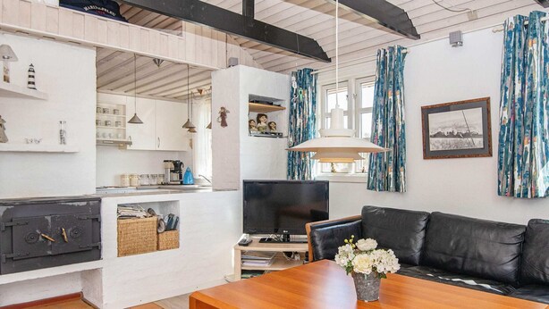 A modern living room with a wooden coffee table, black leather sofa, and a TV. - 6 Person Holiday Home in Hvide Sande-by Traum (Hvide Sande)