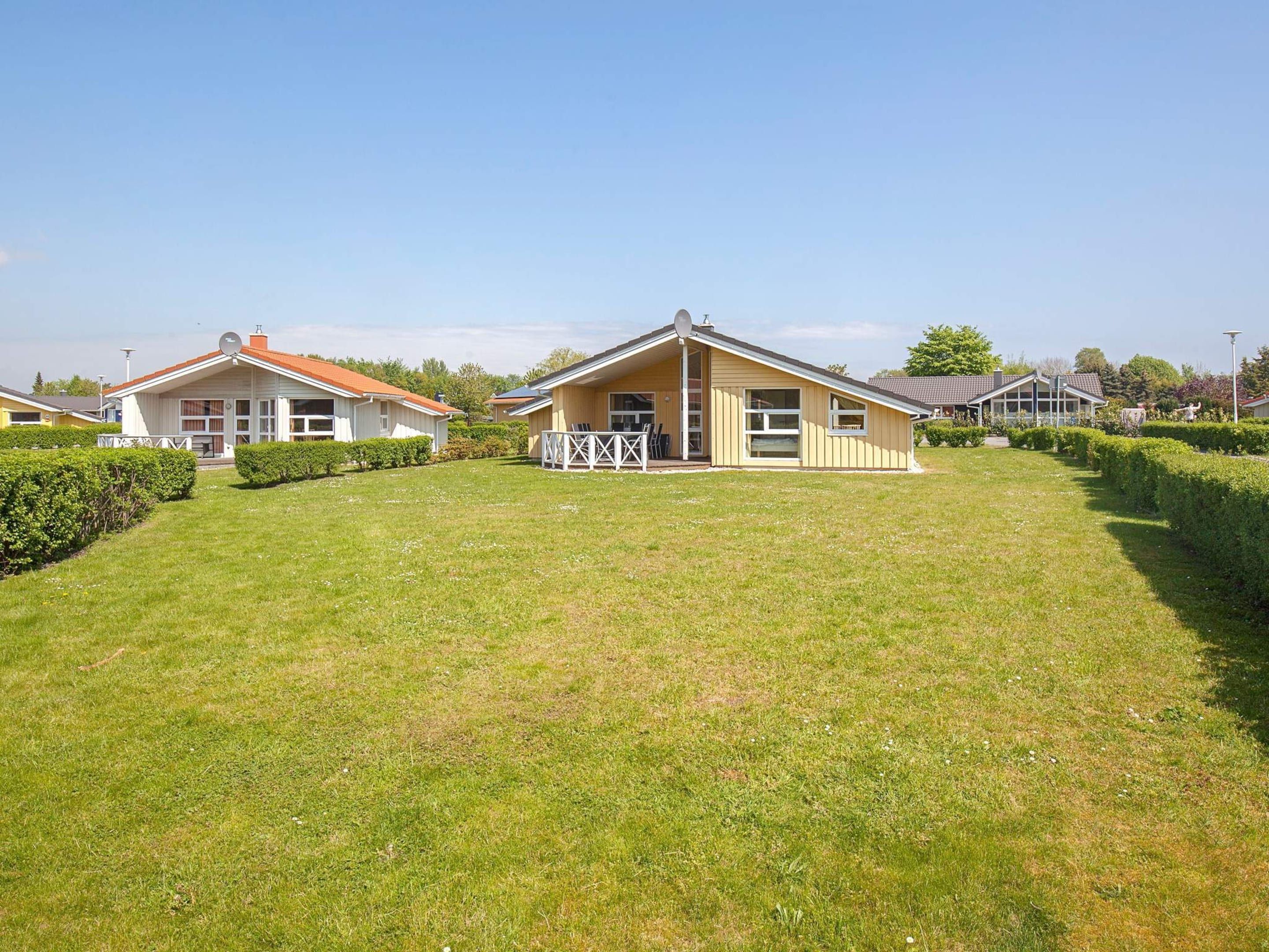A row of single-story houses with a well-maintained lawn and hedges.