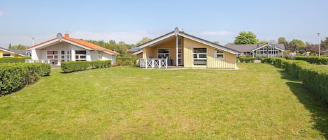 Une rangée de maisons de plain-pied, avec une pelouse et des haies bien entretenues.