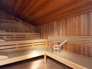 A sauna room with wooden benches and a wooden bucket. - Holiday Home in GrÃ¶mmitz (Groemitz)